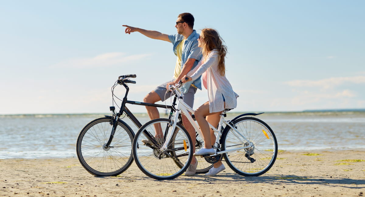 En man och en kvinna med cyklar vid en strand.