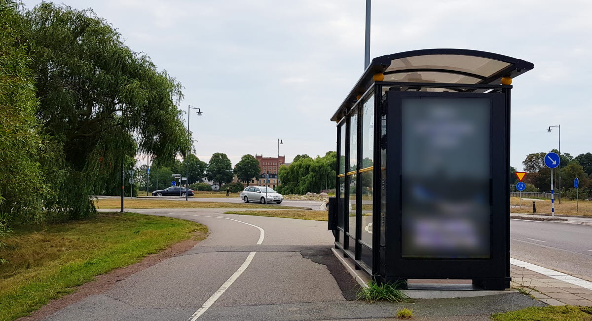 Bild på en cykelväg som går bakom en hållplats. 