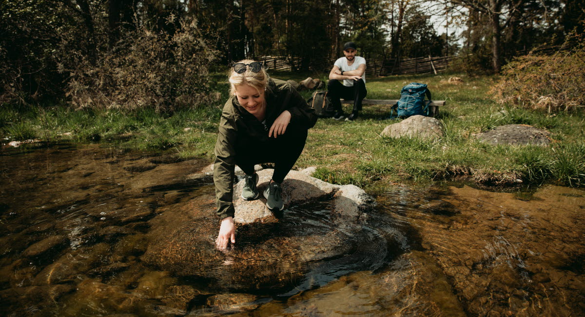 Två personer vilar vid en sjö i skogen.