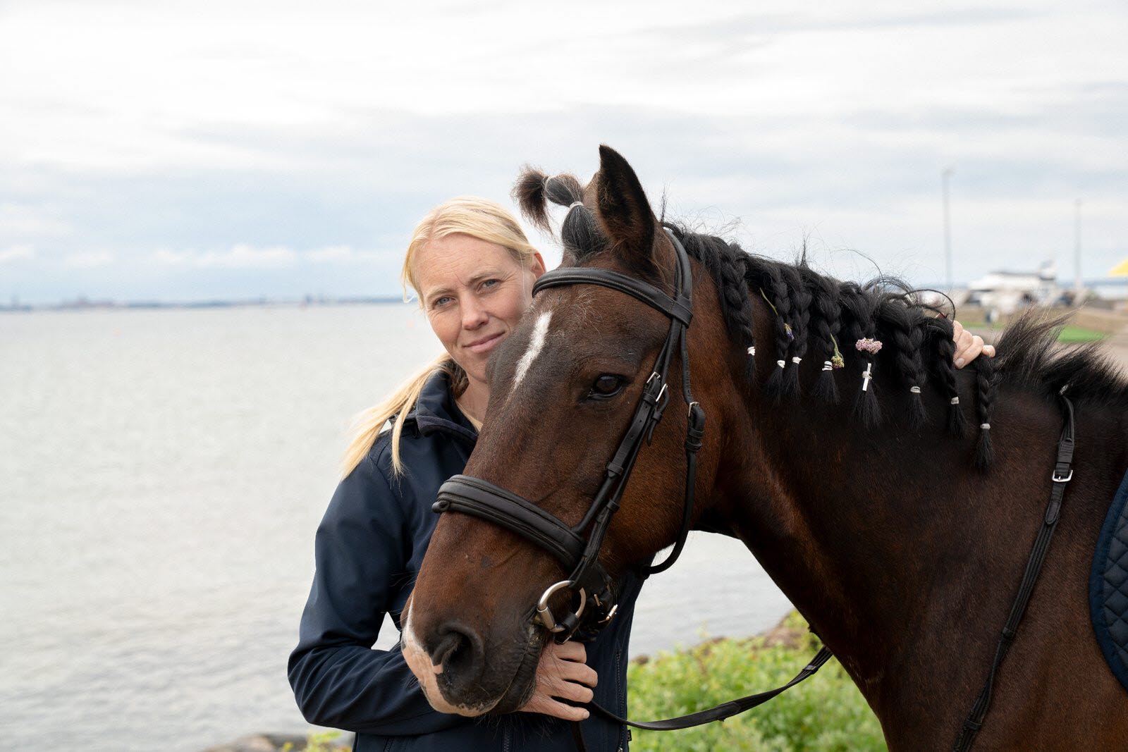 Lovisa Andersson står med sin häst vid vattnet. 